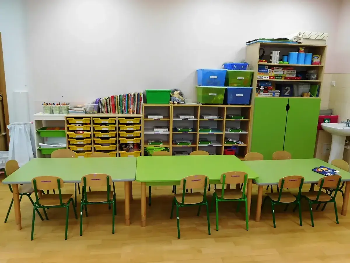 Sala przedszkolna z regałami pełnymi zabawek i pomocy