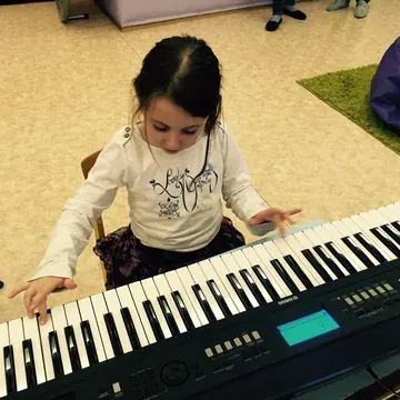 Dziecko gra na keyboardzie podczas zajęć muzycznych