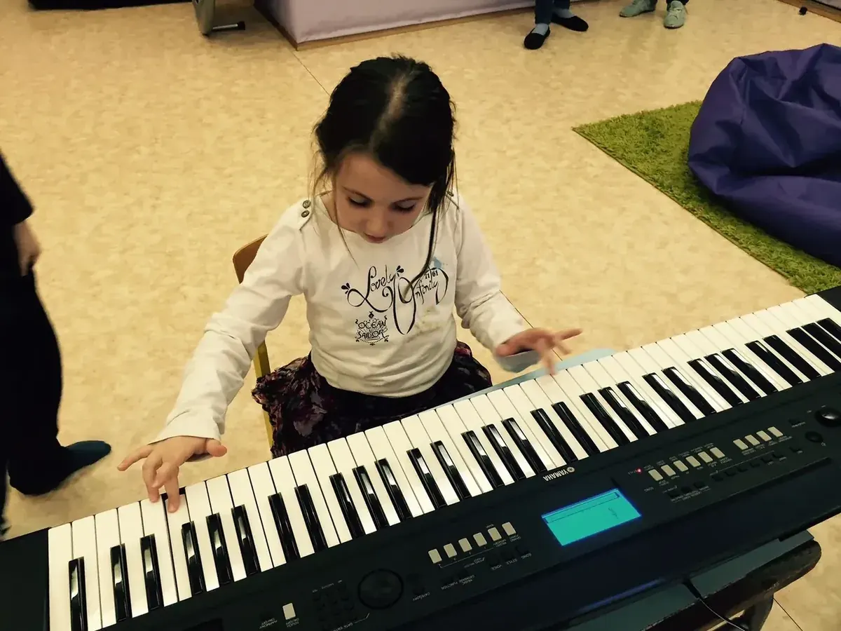 Dziecko grające na keyboardzie podczas zajęć muzycznych